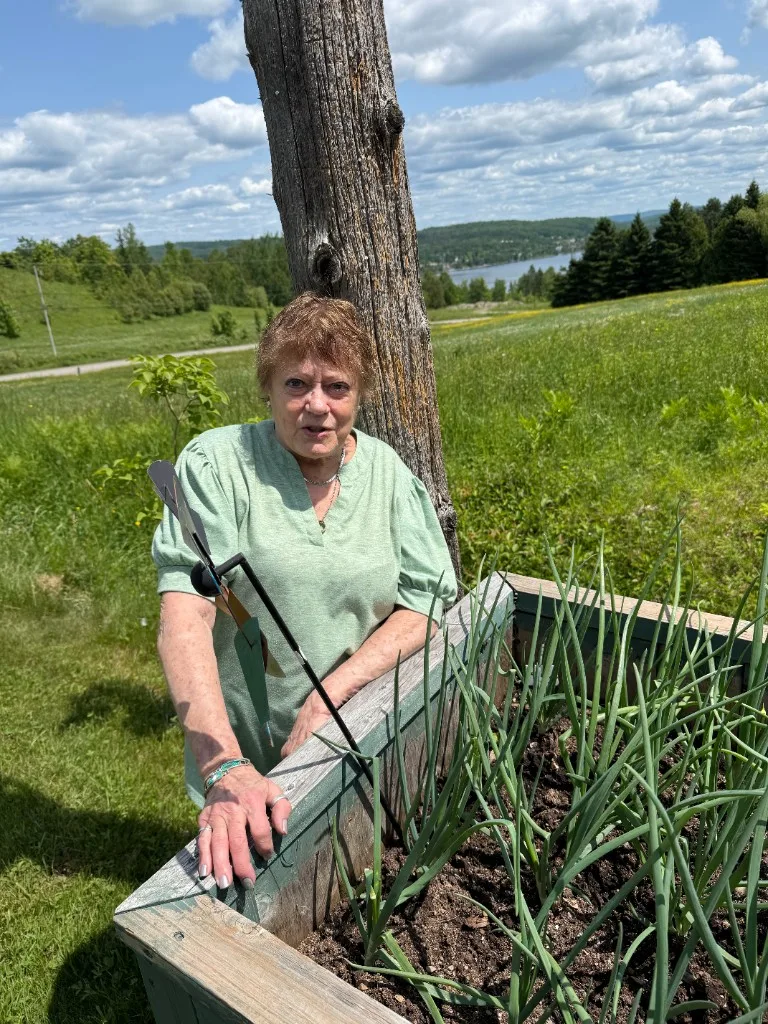 Maxime's mother at her garden, standing by a raised vegetable bed