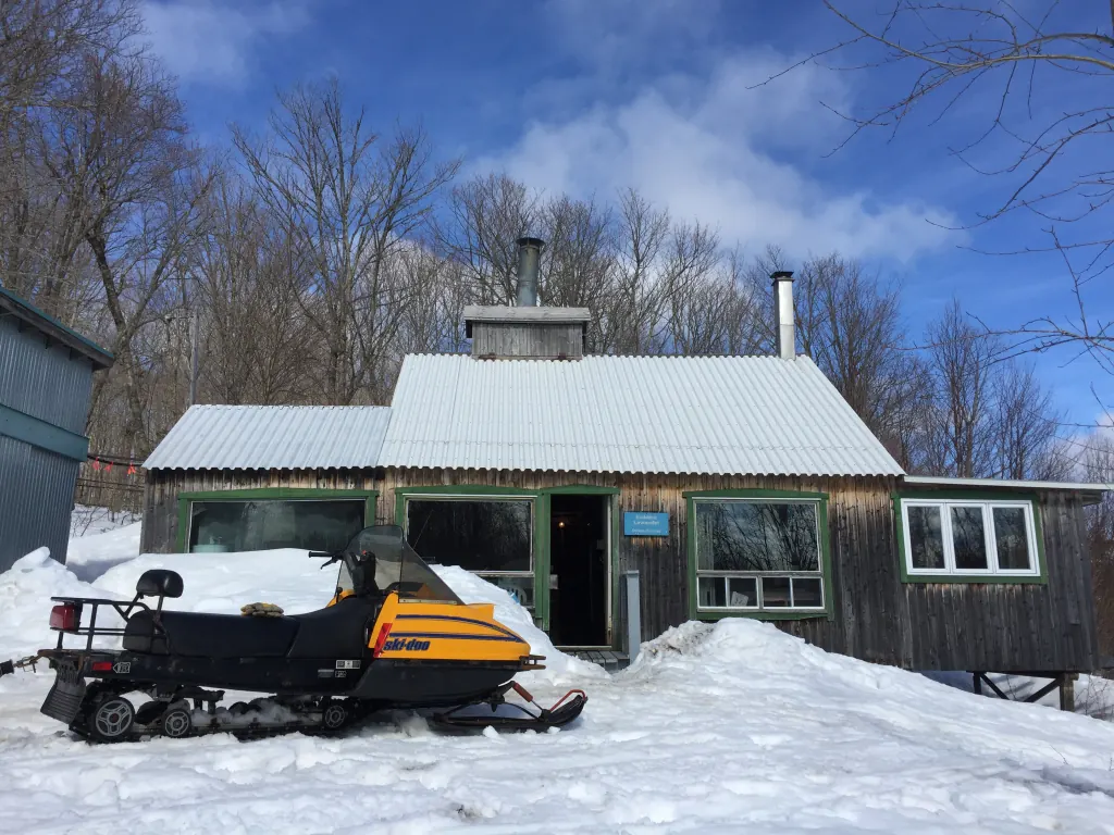 The sugar shack in winter, with a Ski-Doo parked in the snow